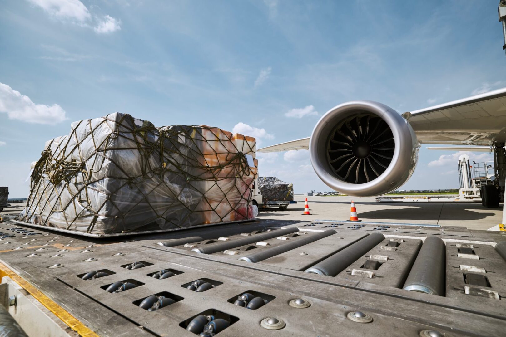 Preparation freight airplane before flight. Loading of cargo containers against jet engine of plane.